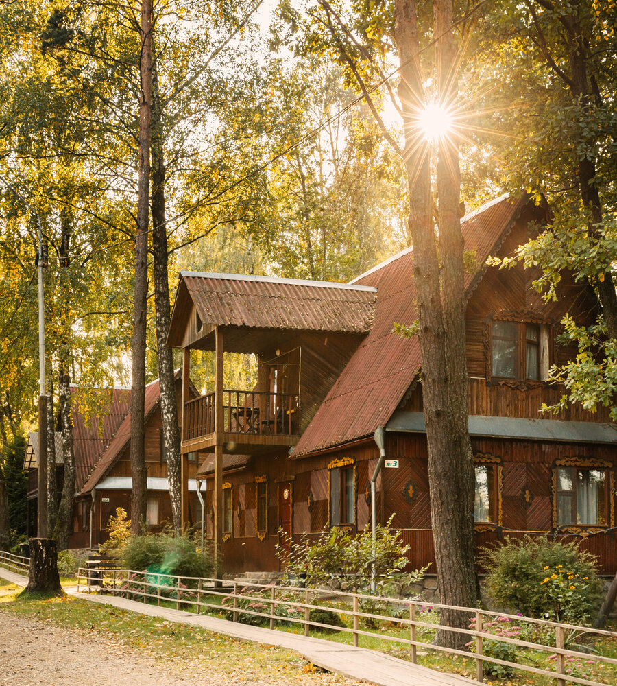 Tourist House For Rest. Wooden House In Forest In Sunny Autumn Day.